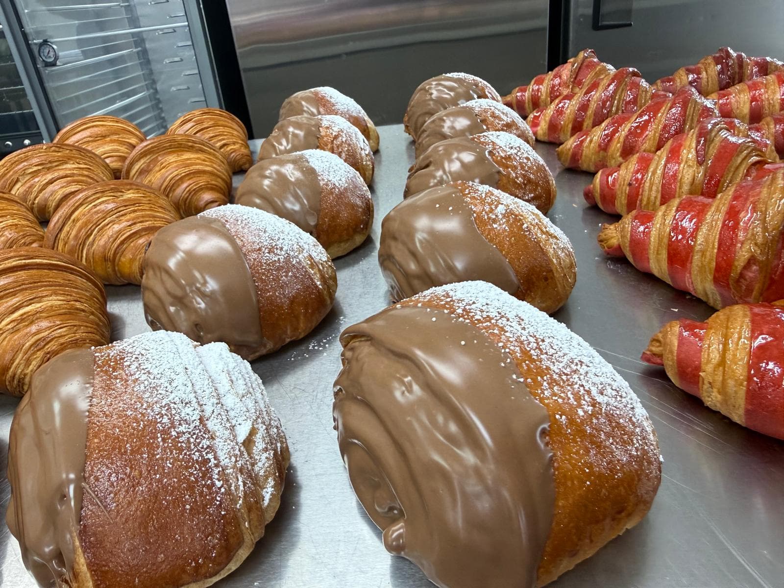 Chocolate-dipped buns beside freshly baked croissants